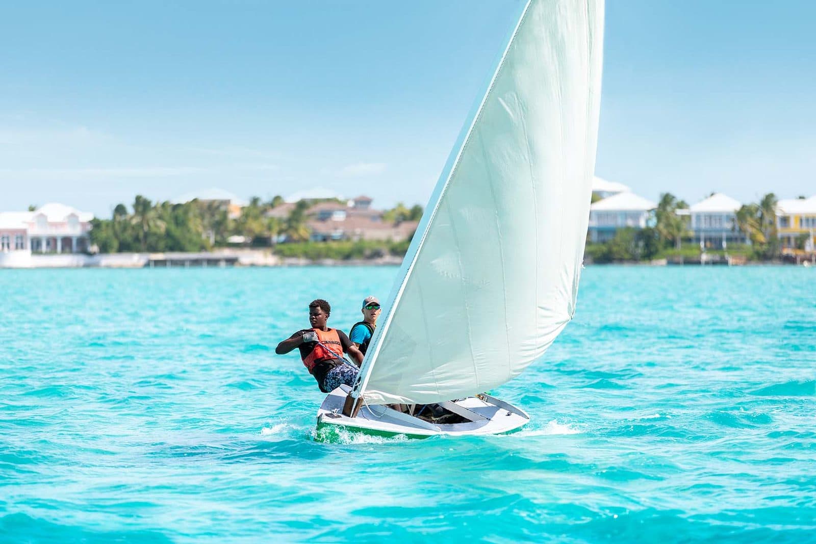 Two people sailing a small boat on turquoise water off Great Exuma