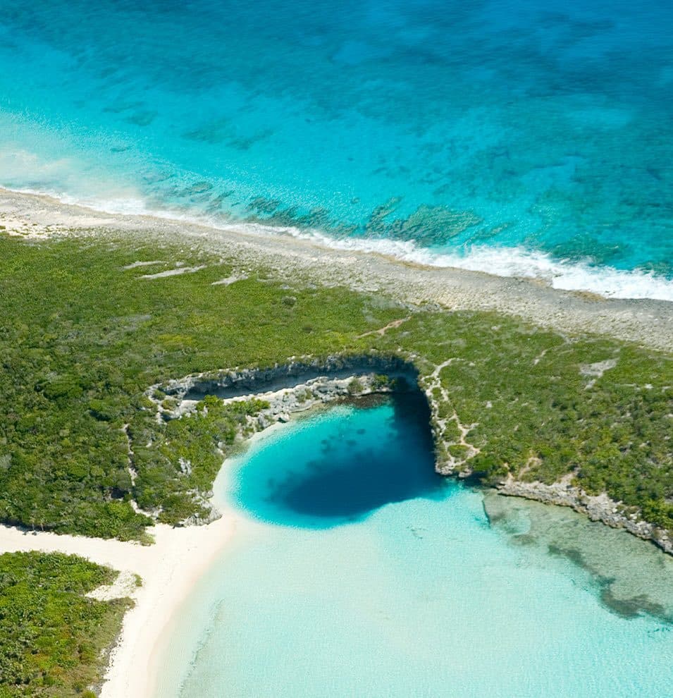 Aerial view of Dean's Blue Hole beside a white beach on Long Island