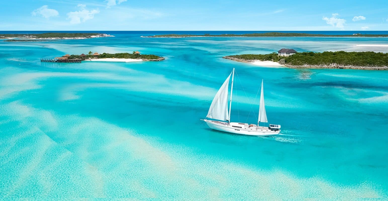 A sailboat anchored among small cays in clear shallow water in The Bahamas